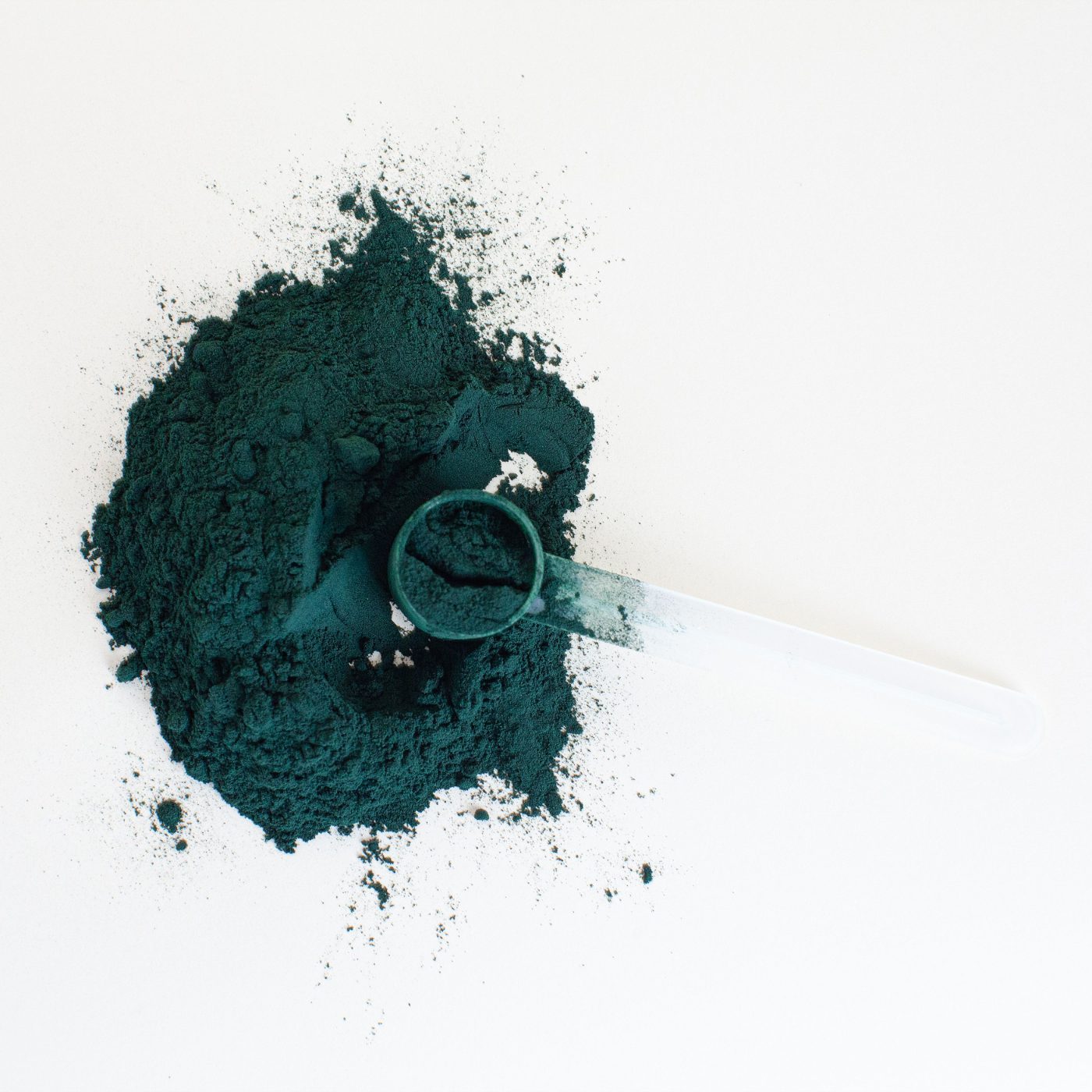 Premium green nutrition supplement powder with measuring scoop on a clean white surface